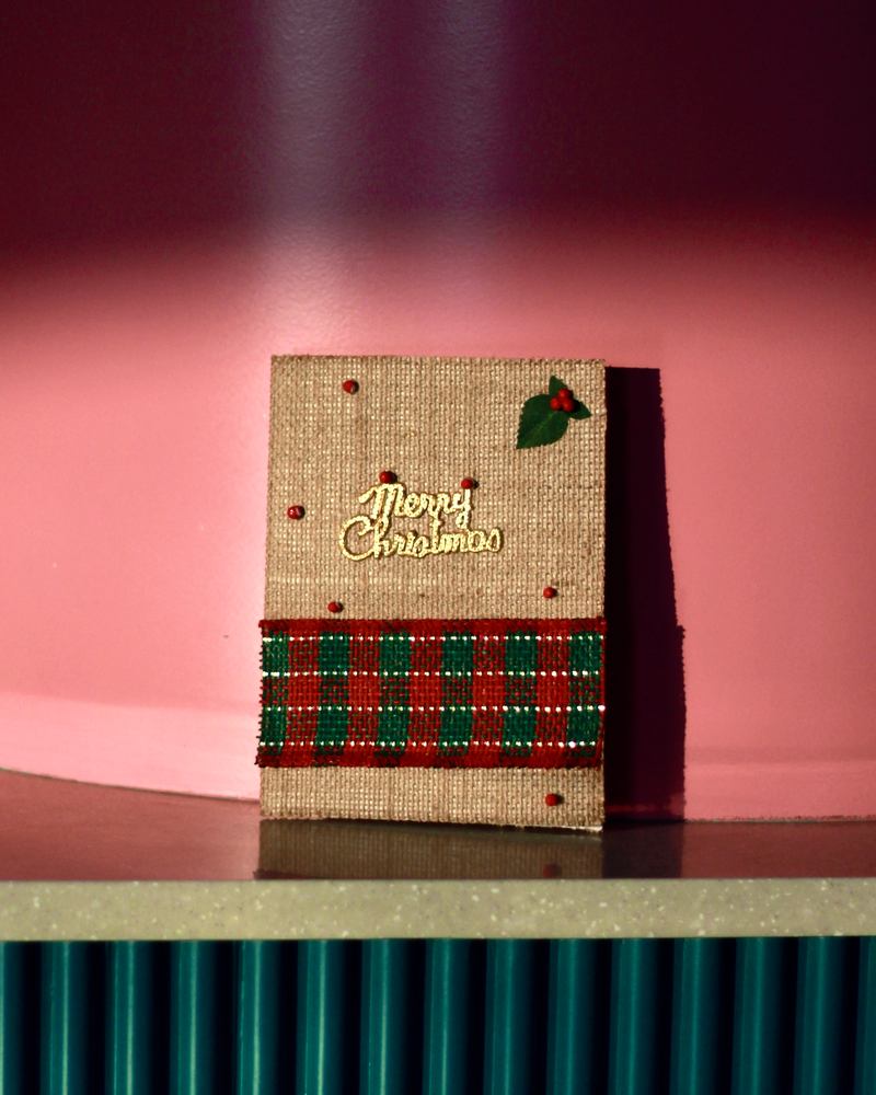 Handmade jute Christmas card on a pink shelf